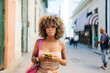 © Daniel Gonzalez/Stocksy - Cuban woman with smartphone on street