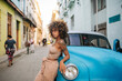 © Daniel Gonzalez/Stocksy - Confident Cuban female leaning on blue car