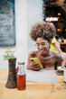 © Daniel Gonzalez/Stocksy - Happy Cuban woman using mobile phone in cafe