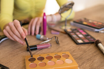 Close-up photo of woman doing her make up on the table in living room.