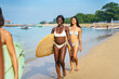 © Jovo Jovanovic/Stocksy - Cheerful diverse women carrying surfboards and walking on seacoast
