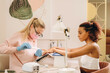 © Alina Hvostikova/Stocksy - Smiling black woman getting manicure