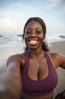 © Jovo Jovanovic/Stocksy - Smiling woman in sportswear taking selfie at the beach