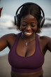 © Jovo Jovanovic/Stocksy - Happy woman in sportswear listening music on headphones at the beach