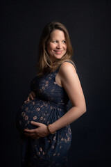 Mulher grávida sorrindo segurando a foto da barriga no estúdio