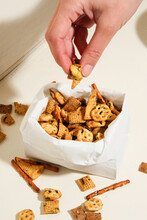 Hand Grabbing Chex Mix Snack From Paper Bag. 