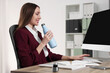 © New Africa - Woman holding light blue thermos bottle at workplace