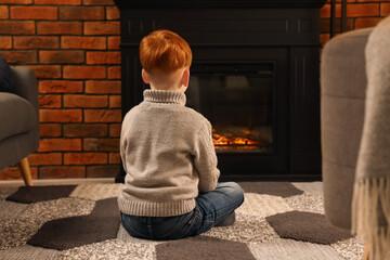 Poster - Boy siting on floor near fireplace at home, back view