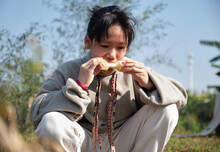 Asian girl, eating sugar cane in the field of the farm