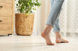 © New Africa - Woman stepping barefoot in room at home, closeup with space for text. Floor heating