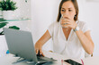 © Olga Moreira/Stocksy - Woman drinking water while working in her home office