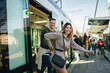 © Daniel Gonzalez/Stocksy - Happy young couple getting off train and smiling
