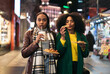 © Pedro Merino/Stocksy - Young black women eating fast food on the street at night