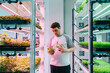 © Daniel Gonzalez/Stocksy - Man standing between shelves in greenhouse with plants