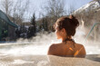 © Danil Nevsky/Stocksy - Young woman sitting in hot spring pool in winter