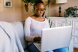 © Serena Burroughs/Stocksy - Smiling pre-teen with glasses sitting on couch at home with laptop