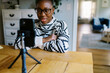 © Serena Burroughs/Stocksy - Young smiling black girl wearing glasses recording herself with phone