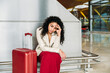 © David Prado/Stocksy - Upset woman sitting near luggage in airport