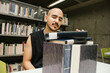 © Laura Herrera/Stocksy - Man looks at a pyle of books