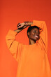 © BONNINSTUDIO/Stocksy - Cheerful woman standing in orange wall