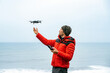 © David Prado/Stocksy - Male explorer operating drone near ocean