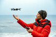 © David Prado/Stocksy - Male explorer operating drone near ocean