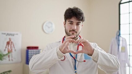 Sticker - Young hispanic man doctor smiling doing heart gesture with hands at clinic