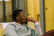 © qunica.com - A side view photo of black male person sitting on a sofa at the office and thinking something