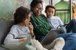 © Studio Marmellata/Stocksy - Black mother sitting with sons using gadgets
