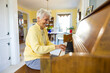 © Raymond Forbes LLC/Stocksy - Happy Senior Citizen woman at Home playing piano keyboard big smile