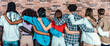 Back view of group of youth multi racial friends they embrace together in front of a brick wall - Diversity, community, ethnicity and people concept