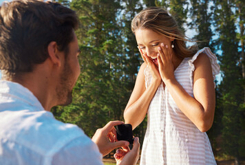 Poster - Man, woman and engagement proposal by woods on vacation with surprise, wow or happiness in sunshine. Couple, marriage offer and ring in nature for romance, love and happy on summer holiday by forrest