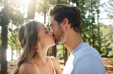 Wall Mural - Couple kiss in forest, love and summer with freedom and adventure, affection in relationship and care outdoor. People together in nature park, commitment and trust with romance, content and sunshine