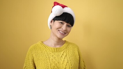 Canvas Print - Young chinese woman smiling confident wearing christmas hat over isolated yellow background