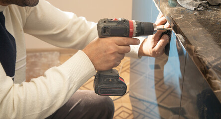 Poster - Worker fixing kitchen cabinet using cordless screwdriver.