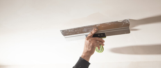 Wall Mural - Worker is applying putty on a wall. Renovating house