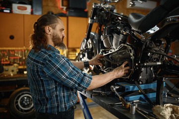 Man mechanic fixing motorcycle engine working at garage workshop