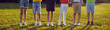 © Studio Romantic - Little children in the park. Group of unrecognizable boys and girls in casual summer clothes standing in a row on green grass. Cropped shot, kids' legs. Banner or header background
