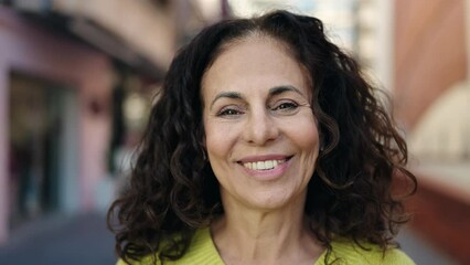 Wall Mural - Middle age hispanic woman smiling confident at street