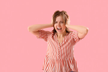 Wall Mural - Angry young woman suffering from loud noise on pink background