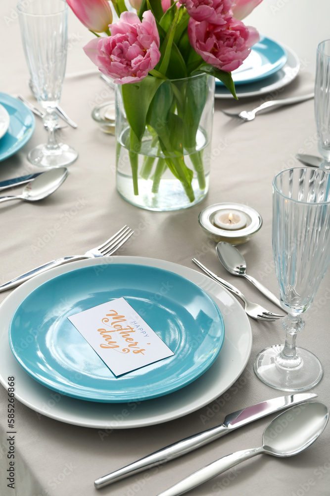 Setting for Mother's Day celebration and vase with tulip flowers on table