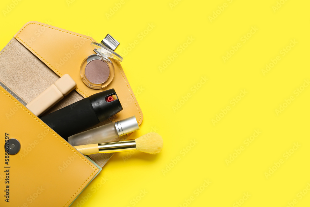 Bag with makeup products and pepper spray on yellow background, closeup