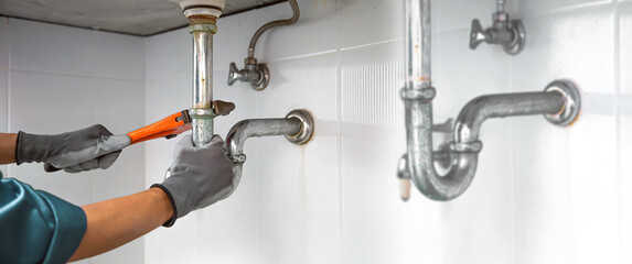 Wall Mural - Technician plumber using a wrench to repair a water pipe under the sink. Concept of maintenance, fix water plumbing leaks, replace the kitchen sink drain, cleaning clogged pipes is dirty or rusty.