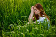 © VICHIZH - sad woman sitting in tall green grass on a sunny day