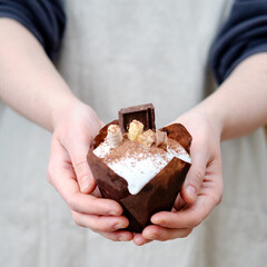 Wall Mural - Woman holding glazed Easter cakes decorated with chocolate and sweets, home kitchen background