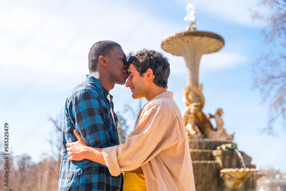 Couple of multi-ethnic men in a city fountain, lgbt concept, in a ...
