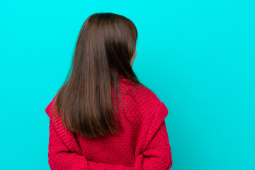 Wall Mural - Little caucasian girl isolated on blue background in back position and looking back