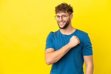 Wall Mural - Young handsome caucasian man isolated on yellow background celebrating a victory