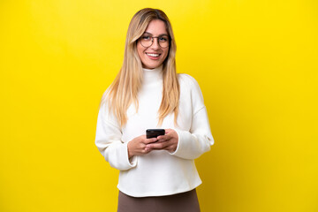 Wall Mural - Young Uruguayan woman isolated on yellow background sending a message with the mobile