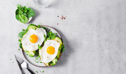 Wall Mural - Avocado Sandwich with Fried Egg, Spinach and Green Sprouts, Healthy Breakfast or Snack on Bright Background